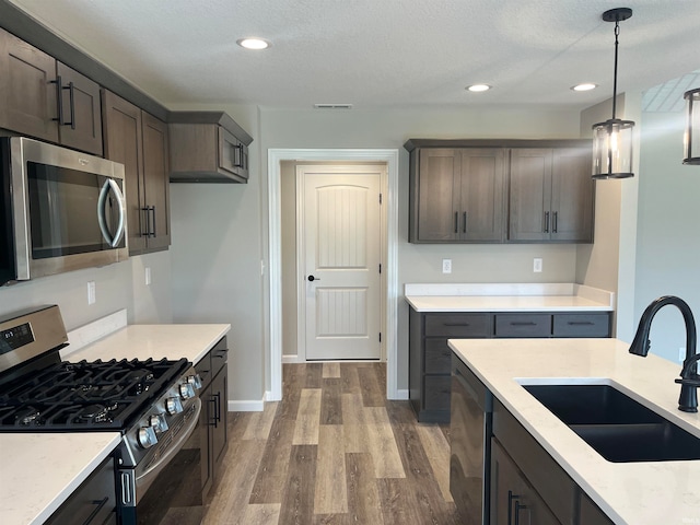 kitchen with sink, a textured ceiling, hanging light fixtures, and appliances with stainless steel finishes