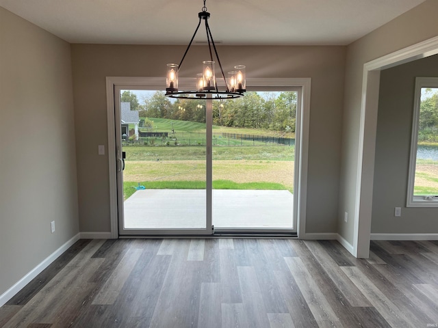 unfurnished dining area featuring hardwood / wood-style flooring and an inviting chandelier