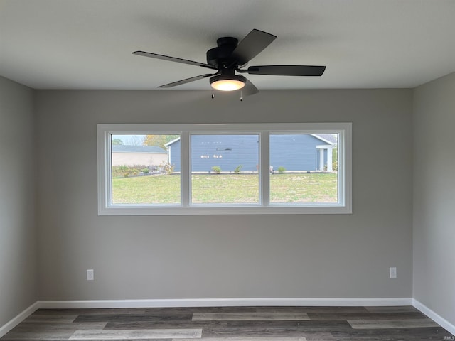 empty room with ceiling fan, plenty of natural light, and dark wood-type flooring