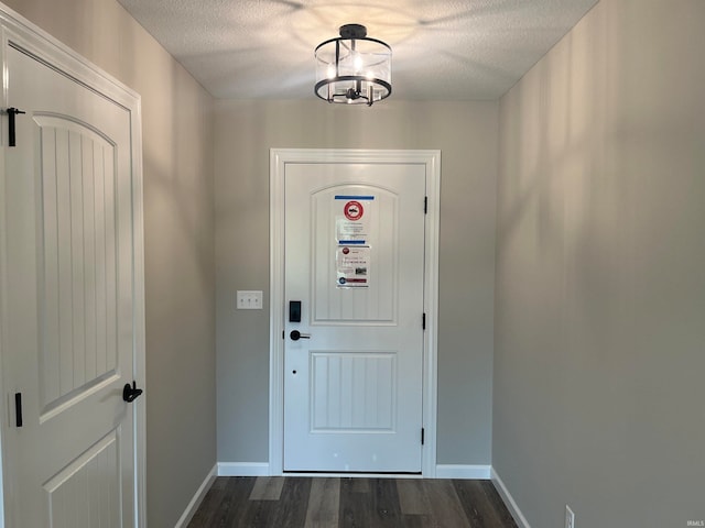 doorway with dark hardwood / wood-style flooring, a textured ceiling, and a chandelier