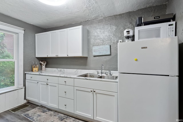 kitchen featuring a wealth of natural light, white cabinetry, sink, and white appliances