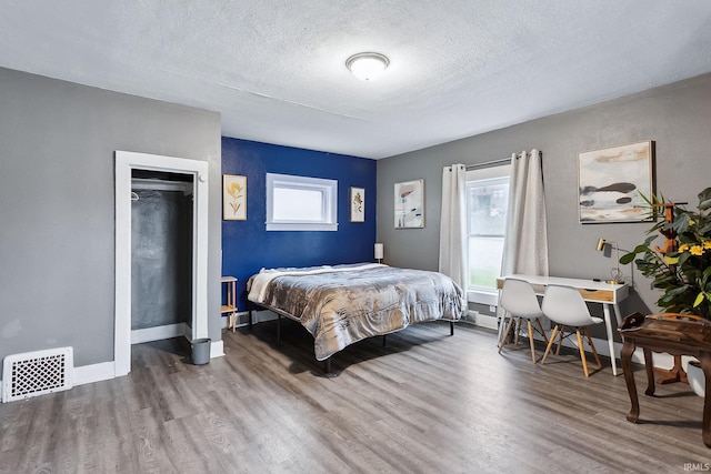 bedroom with multiple windows, a textured ceiling, and hardwood / wood-style flooring