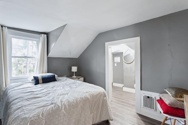 bedroom with light hardwood / wood-style floors and lofted ceiling