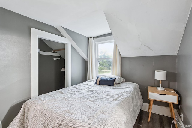 bedroom featuring dark wood-type flooring and vaulted ceiling