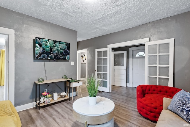 living room with wood-type flooring, a textured ceiling, and french doors