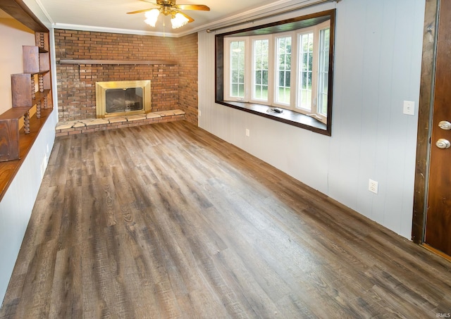 unfurnished living room featuring wood-type flooring, ceiling fan, a fireplace, and crown molding