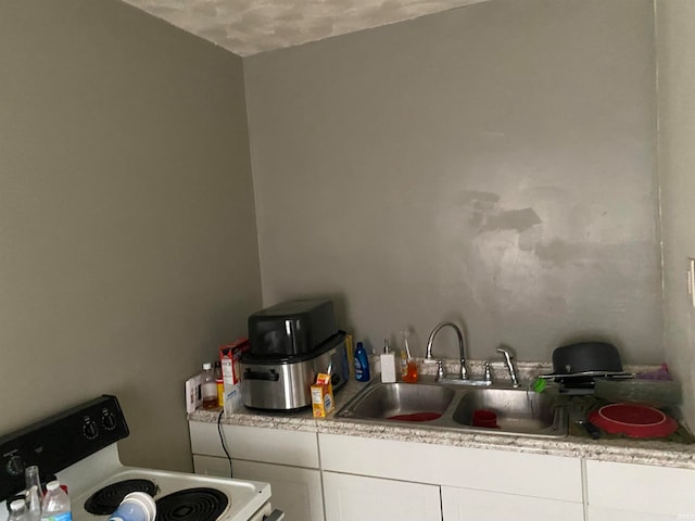 kitchen with white cabinets, white range, a textured ceiling, and sink