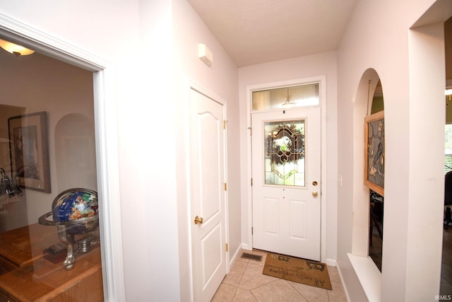 doorway to outside with a textured ceiling and light tile patterned floors