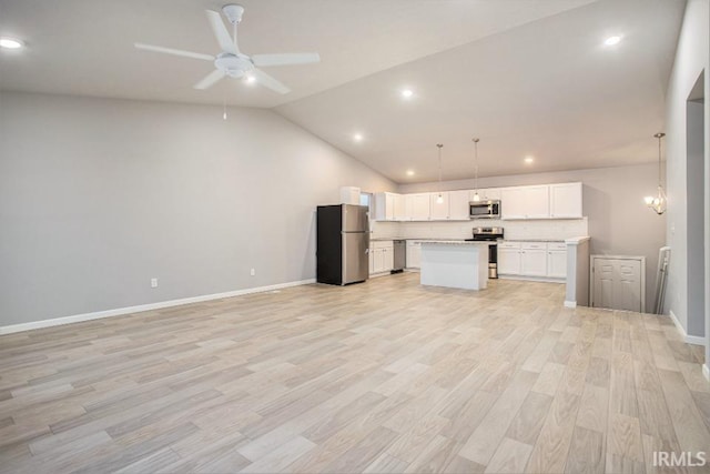 kitchen featuring lofted ceiling, white cabinets, ceiling fan with notable chandelier, pendant lighting, and stainless steel appliances