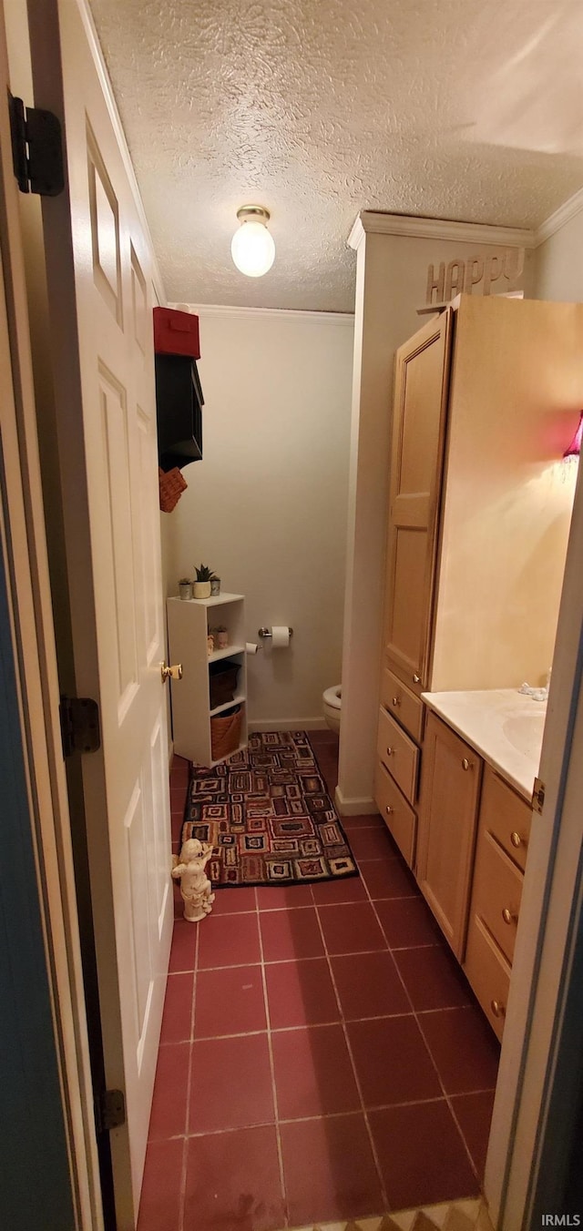 bathroom featuring tile patterned flooring, crown molding, a textured ceiling, toilet, and vanity