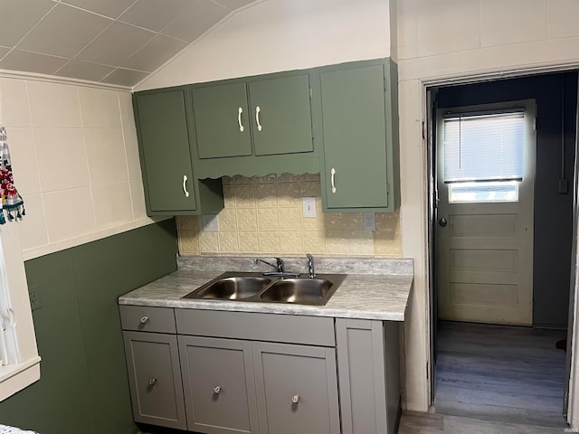 kitchen featuring wood-type flooring, green cabinetry, lofted ceiling, and sink