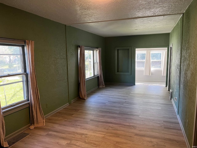 unfurnished room featuring a healthy amount of sunlight, vaulted ceiling, and light hardwood / wood-style flooring