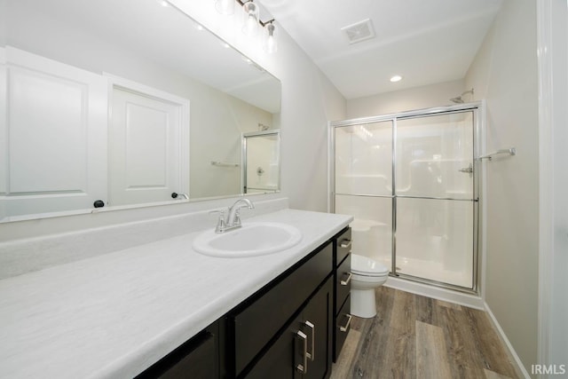 bathroom with hardwood / wood-style floors, vanity, toilet, and a shower with door