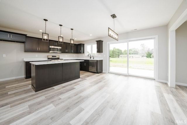 kitchen with hanging light fixtures, stainless steel appliances, a center island, and a wealth of natural light