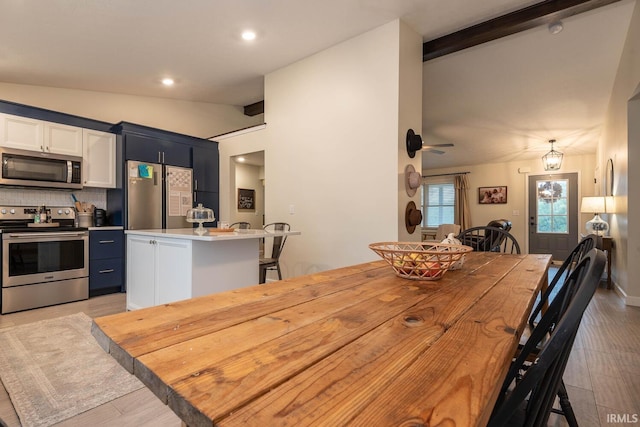 dining space with lofted ceiling with beams and light hardwood / wood-style floors