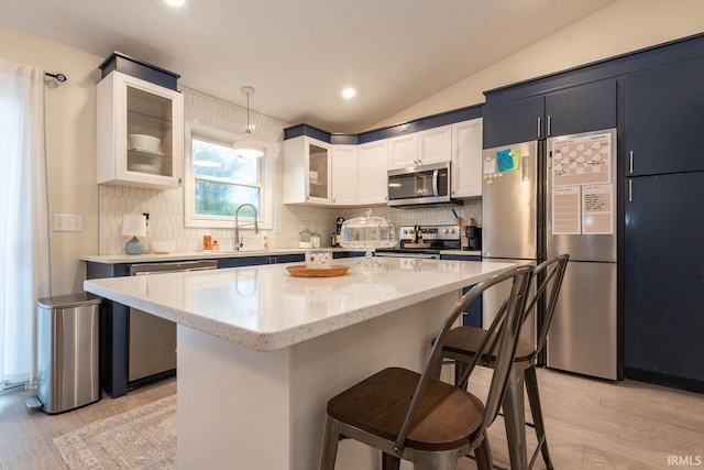 kitchen with vaulted ceiling, backsplash, a kitchen island, pendant lighting, and stainless steel appliances