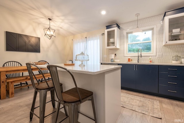 kitchen with white cabinets, pendant lighting, sink, a center island, and light hardwood / wood-style floors