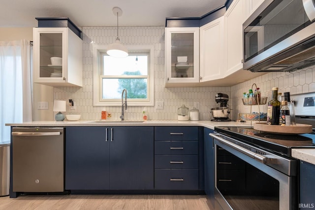 kitchen featuring appliances with stainless steel finishes, light hardwood / wood-style floors, white cabinets, blue cabinetry, and sink