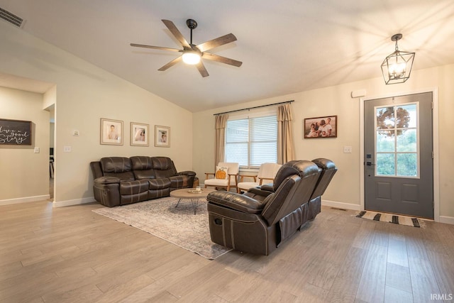 living room with ceiling fan with notable chandelier, lofted ceiling, light hardwood / wood-style flooring, and a wealth of natural light