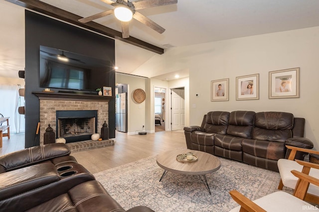 living room featuring a brick fireplace, vaulted ceiling with beams, ceiling fan, and hardwood / wood-style floors