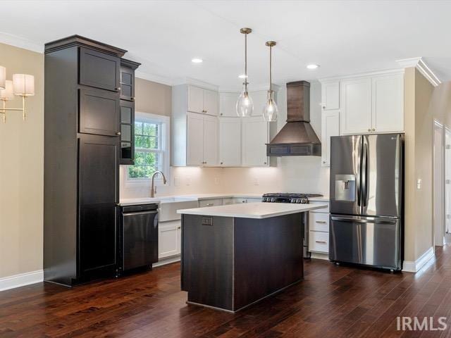 kitchen with a kitchen island, decorative light fixtures, wall chimney range hood, stainless steel appliances, and dark hardwood / wood-style floors