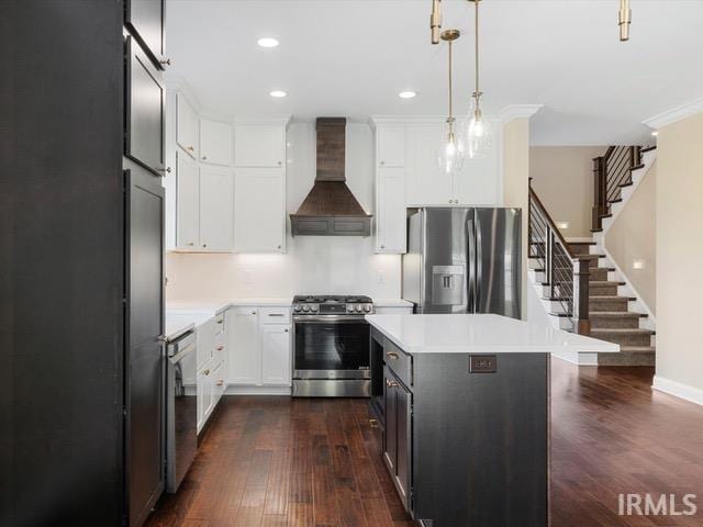 kitchen with dark hardwood / wood-style floors, hanging light fixtures, a kitchen island, custom exhaust hood, and appliances with stainless steel finishes