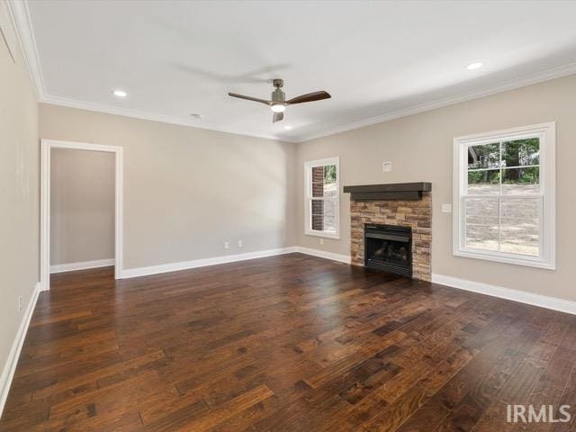 unfurnished living room featuring a stone fireplace, ornamental molding, dark hardwood / wood-style floors, and ceiling fan