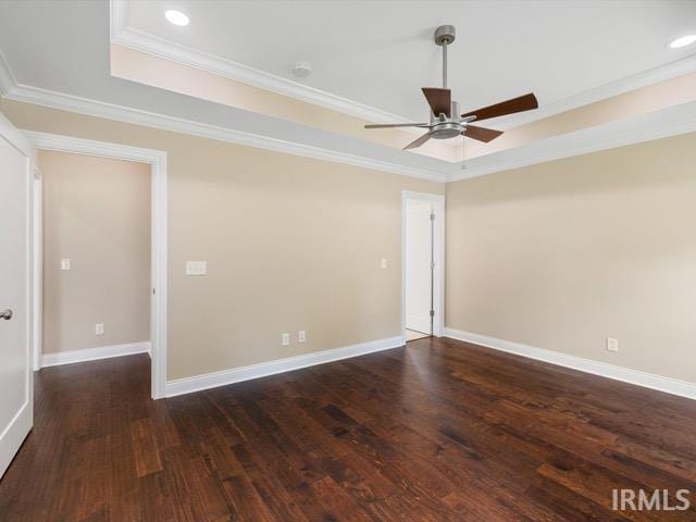 unfurnished room featuring ornamental molding, ceiling fan, a raised ceiling, and dark wood-type flooring