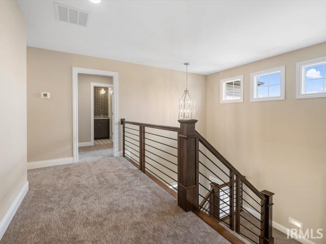 hallway with carpet floors and an inviting chandelier