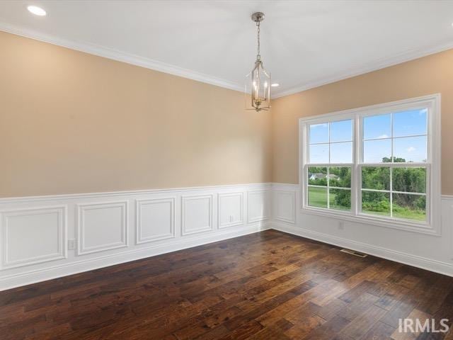 spare room with ornamental molding, dark hardwood / wood-style floors, and an inviting chandelier