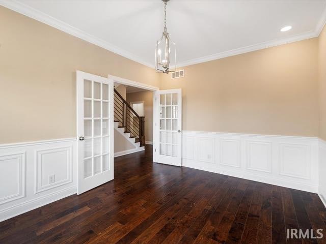 empty room featuring a chandelier, crown molding, french doors, and dark hardwood / wood-style flooring