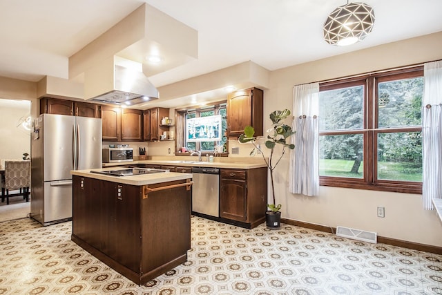 kitchen with exhaust hood, appliances with stainless steel finishes, a wealth of natural light, and a center island