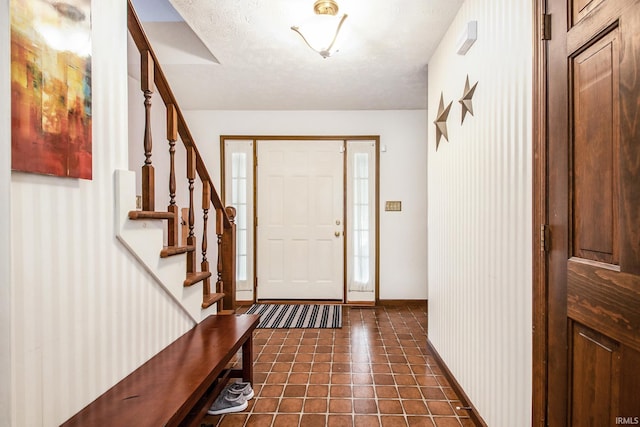 foyer with a textured ceiling and dark tile patterned flooring