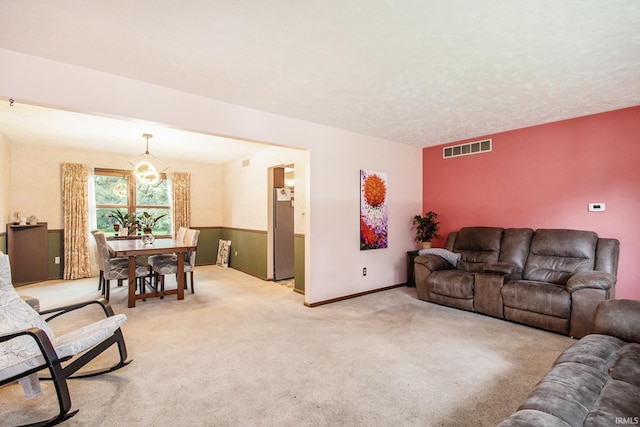 living room with light carpet and an inviting chandelier