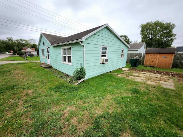 exterior space featuring an outbuilding, a lawn, a storage shed, fence, and cooling unit