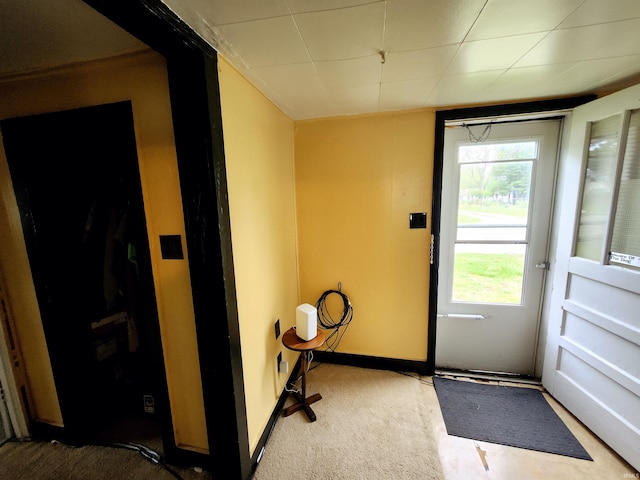 doorway featuring carpet and baseboards