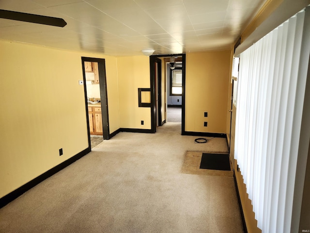 spare room featuring baseboards and light colored carpet