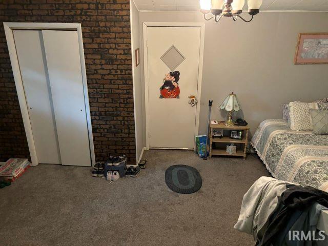 506 Meredith St, Washington, IN 47501 - carpeted bedroom featuring a chandelier and brick wall