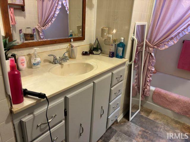 bathroom featuring vanity, tile walls, and shower / bath combo with shower curtain