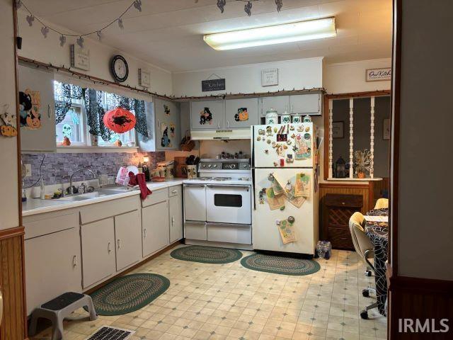 kitchen featuring backsplash, white appliances, and sink