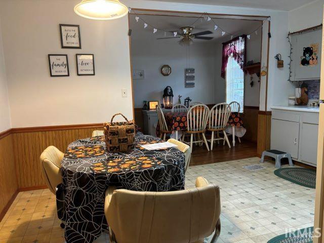 506 Meredith St, Washington, IN 47501 - dining area featuring a ceiling fan, a wainscoted wall, light flooring, and wood walls