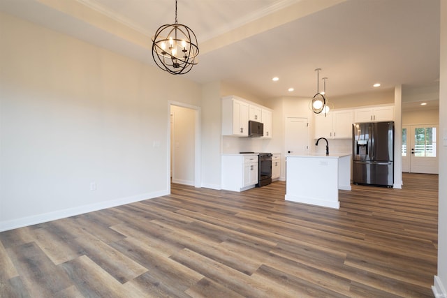 kitchen with an island with sink, hanging light fixtures, white cabinetry, and black appliances