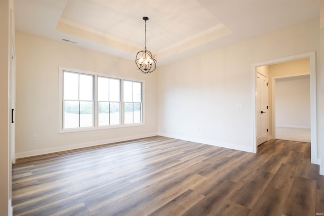 unfurnished room with a raised ceiling, a chandelier, and dark hardwood / wood-style flooring