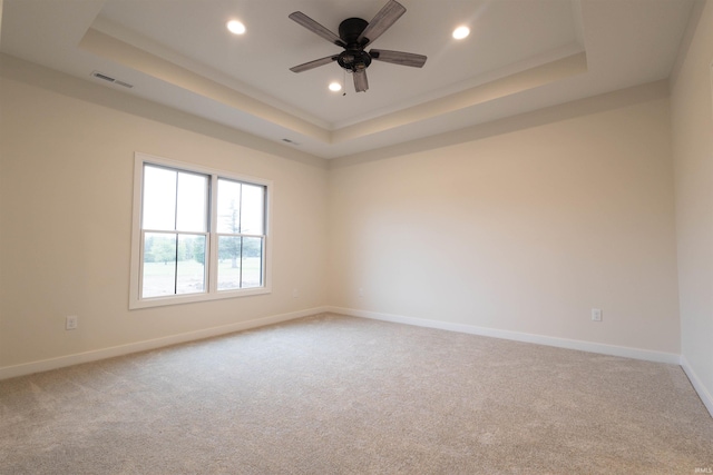 empty room with carpet, a tray ceiling, and ceiling fan