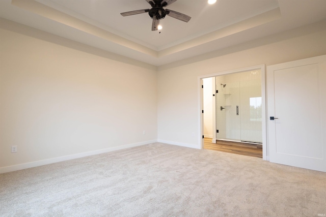 unfurnished room with a tray ceiling, ceiling fan, and light colored carpet