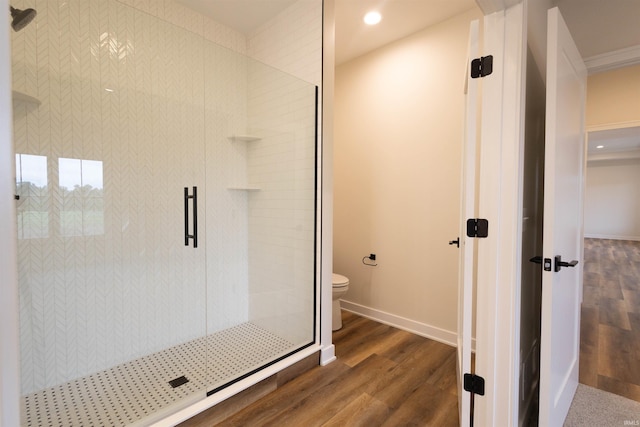 bathroom with ornamental molding, walk in shower, hardwood / wood-style flooring, and toilet