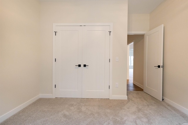 unfurnished bedroom featuring light carpet and a closet