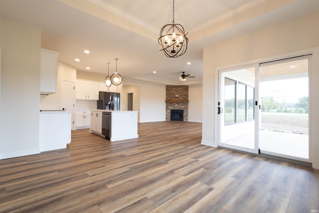 kitchen with white cabinets, a raised ceiling, decorative light fixtures, and a stone fireplace