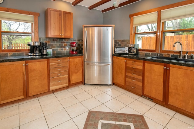 kitchen with beam ceiling, sink, a healthy amount of sunlight, and stainless steel refrigerator