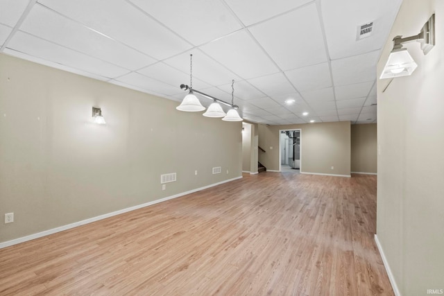 basement with a drop ceiling and light wood-type flooring